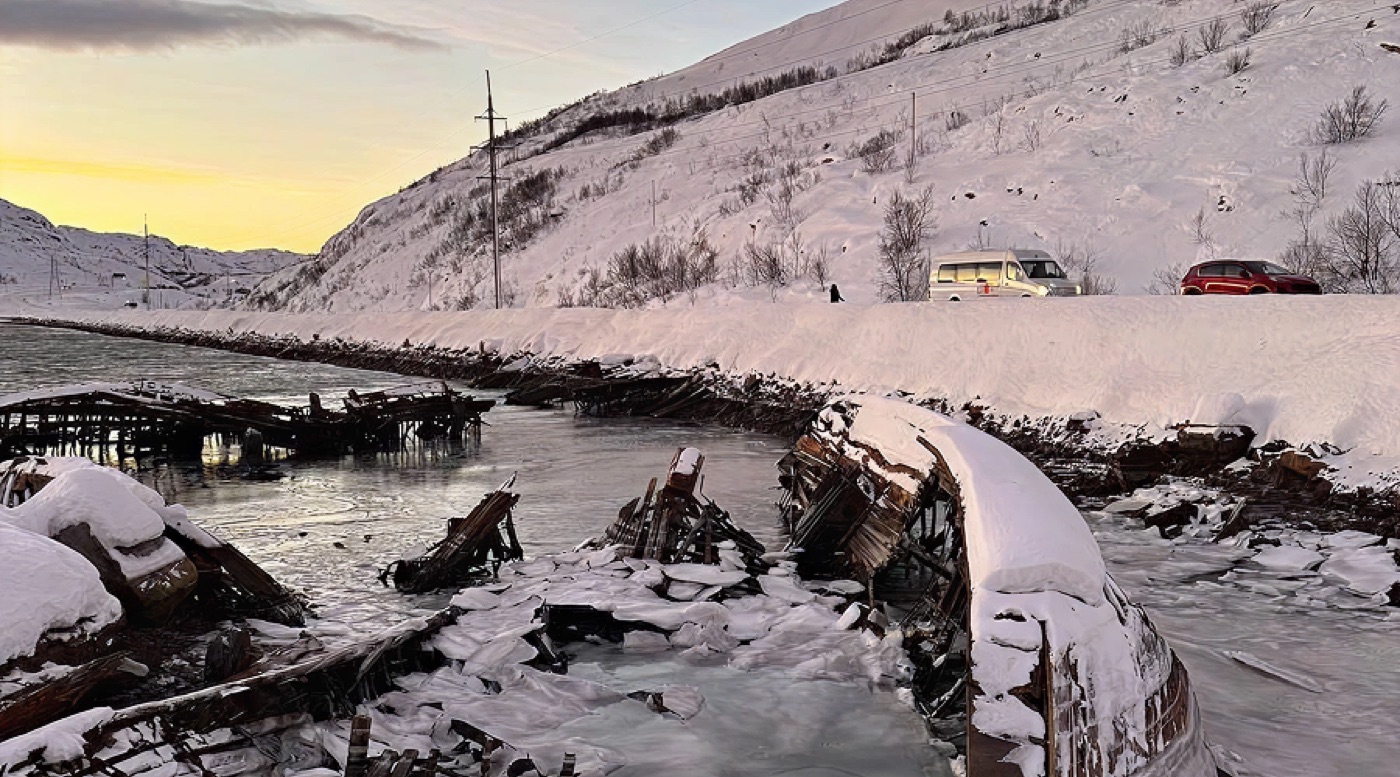 Snow-covered wooden hulls of wrecked fishing vessels in an icy bay