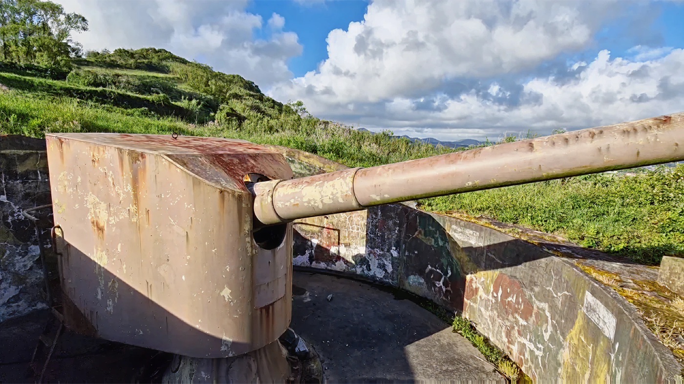 Abandoned WWII coastal artillery gun overlooking green cliffs